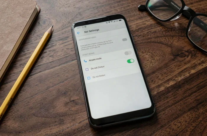 Écran d'un smartphone Android affichant les paramètres du mode avion et du mode Ne pas déranger posé sur un bureau en bois
