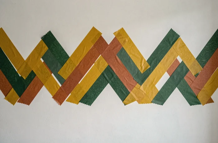 Frise géométrique réalisée avec du masking tape washi coloré sur un mur blanc de chambre d'enfant