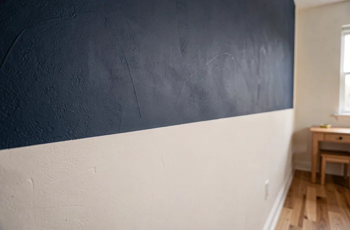 Mur de chambre d'enfant peint en deux couleurs avec une ligne de démarcation nette entre bleu marine et blanc