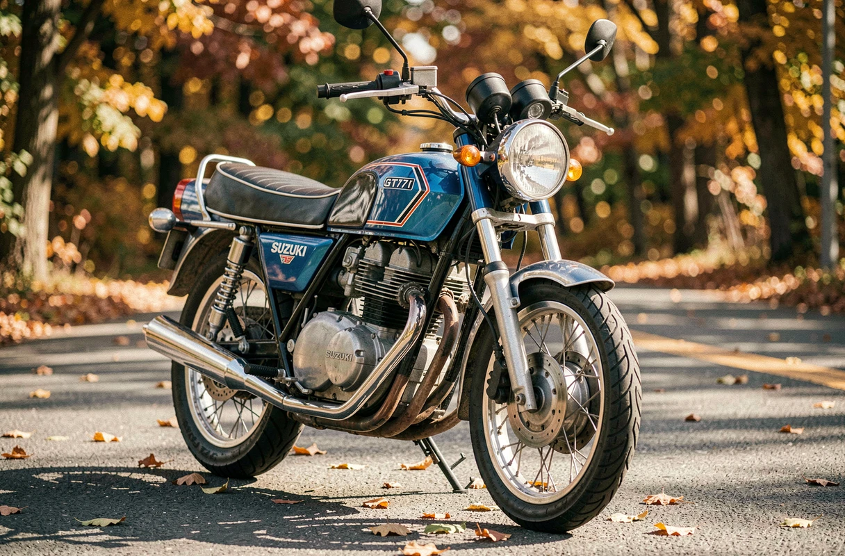 Suzuki GT750 série milieu des années 70 en bleu métallisé restaurée, photographiée en trois quarts avant sur route asphaltée entourée de feuilles d'automne